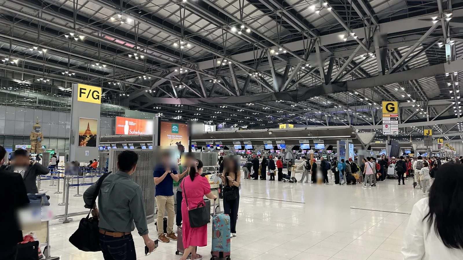 スワンナプーム空港の出発ロビー。チェックインカウンターに並ぶ人々